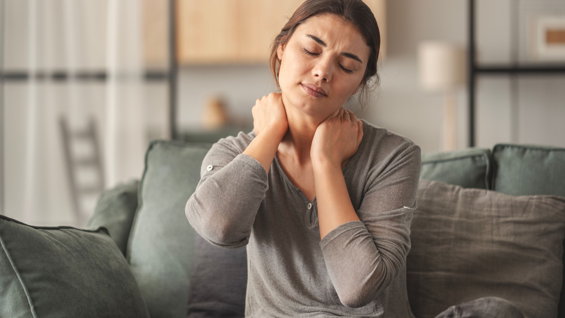 Woman suffering from neck pain in home Woman suffering from neck pain in home