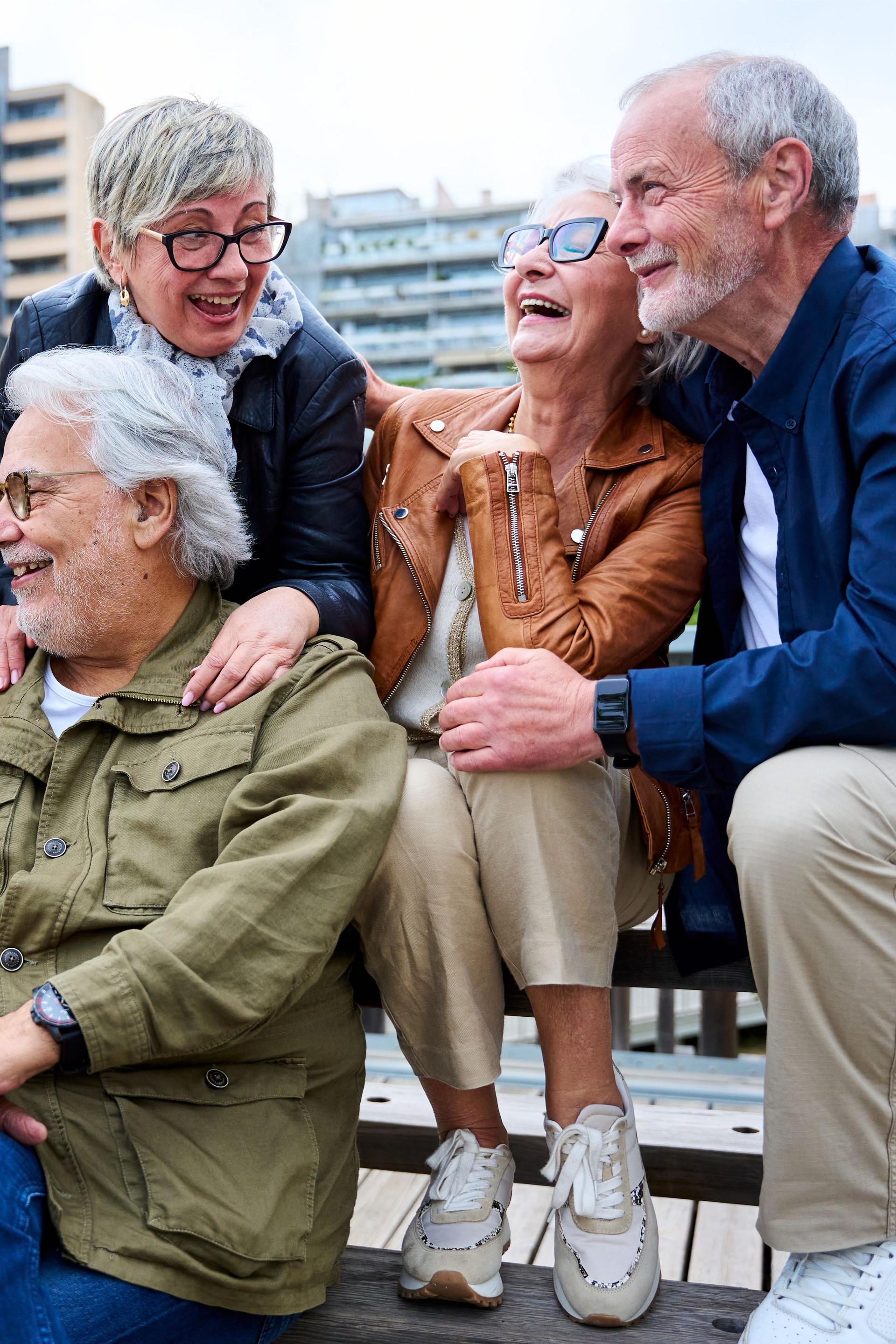 Group of elderly Caucasians friends people having fun laughing together sitting on bench in city. Group of elderly Caucasians friends people having fun laughing together sitting on bench in city.