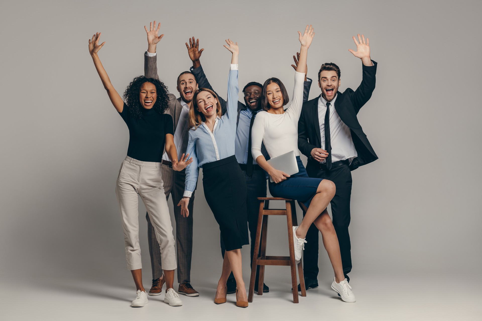 Joyful young business team in formalwear gesturing while standing on beige background Joyful young business team in formalwear gesturing while standing on beige background